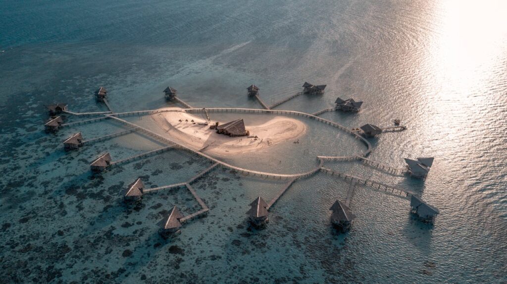 A breathtaking aerial shot of a tropical island resort featuring overwater bungalows and a tranquil sea setting.
